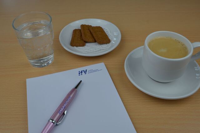 Seminarplatz mit Notizblock, Stift, Wasser und Kaffee